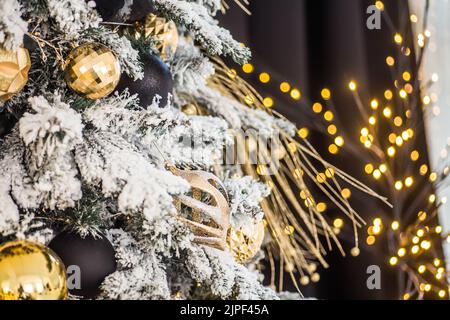 Weihnachtsbaum geschmückt mit Blumen und Vögeln. Originelle Dekorationen auf Ästen von Weihnachtsbaum, Neujahrskonzept. Bokeh Girlanden im Hintergrund Stockfoto