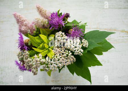 Nahaufnahme eines Straußes wilder Blumen auf einem hölzernen Hintergrund. Rustikaler Stil. Stockfoto