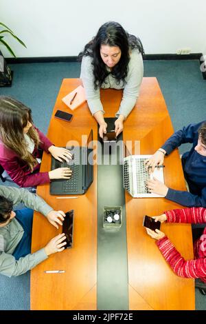 Draufsicht auf eine Gruppe von Mitarbeitern, die am Büromeetingtisch sitzen und Brainstorming sprechen Stockfoto