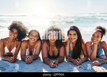 Wo auch immer die Sonne ist, das ist gut so. Porträt einer Gruppe glücklicher junger Frauen, die sich am Strand entspannen. Stockfoto