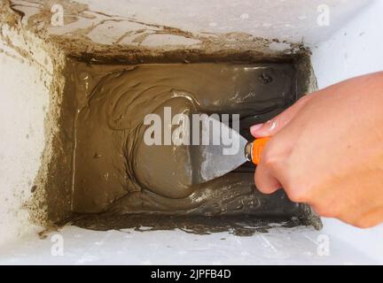 Zementpulver von Hand und Metallkelle gemischt. Vorbereitung der Wandmalerei zu Hause Stockfoto