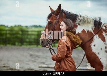 Wenn du ein Pony hast, hast du alles. Ein Teenager-Mädchen, das neben ihrem Pony auf einer Farm steht. Stockfoto