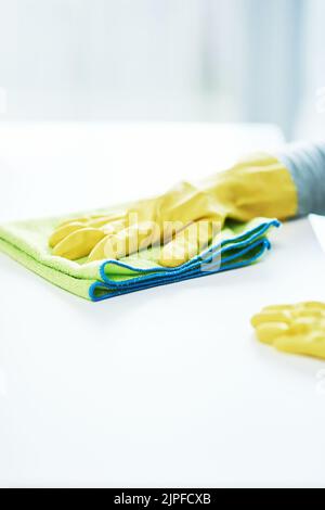 Nicht heute, Keime. Eine unkenntliche Person, die Gummihandschuhe trägt und zu Hause eine Theke abwischt. Stockfoto