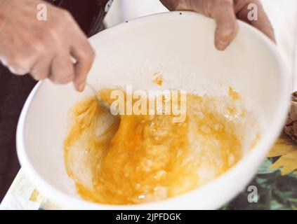 Großmutter bereitet Teig für Pfannkuchen zu Stockfoto