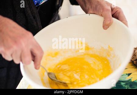 Großmutter bereitet Teig für Pfannkuchen zu Stockfoto