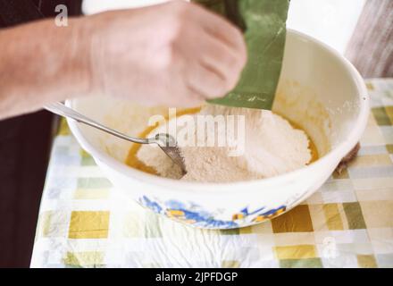 Großmutter bereitet Teig für Pfannkuchen zu Stockfoto