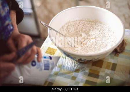 Großmutter bereitet Teig für Pfannkuchen zu Stockfoto