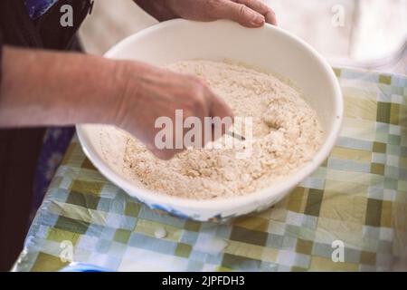 Großmutter bereitet Teig für Pfannkuchen zu Stockfoto