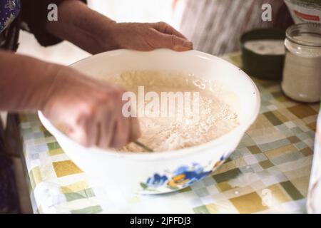 Großmutter mischte Teig für Pfannkuchen Stockfoto