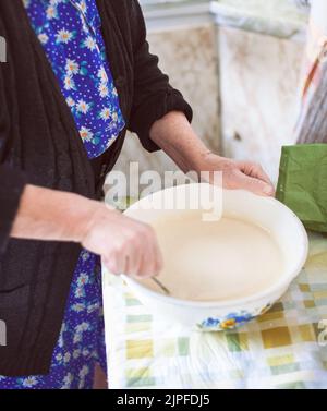 Großmutter mischte Teig für Pfannkuchen Stockfoto