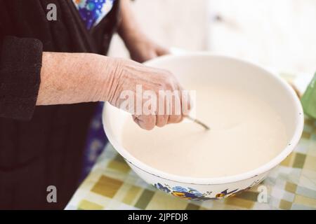 Großmutter mischte Teig für Pfannkuchen Stockfoto