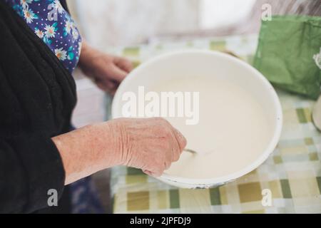 Großmutter mischte Teig für Pfannkuchen Stockfoto