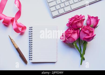 Rosen, um Geist und Sinne klar zu halten. Studioaufnahme eines Tagebuchs und eines Stifts, der mit anderen Stillleben-Objekten vor einem grauen Hintergrund platziert wurde. Stockfoto