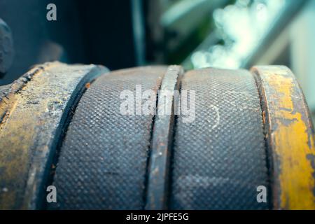 Zwei Antriebsriemen an einer Riemenscheibe in Nahaufnahme. Verschlissene Teile eines alten, hinter dem Traktor stehenden Traktors Stockfoto