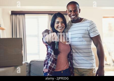 Das ist ein großer Meilenstein für uns. Porträt eines jungen Paares, das die Schlüssel zu ihrem neuen Zuhause hält. Stockfoto