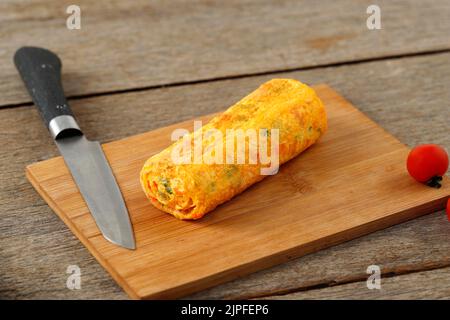 Tamagoyaki, platziert auf einem Holzschneidebrett und japanischem Eierrollen-Omelett, Zubereitungsnahrung Stockfoto