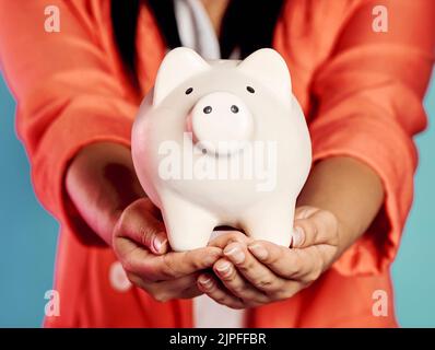 Nahaufnahme der Hände, die ein Sparschwein mit ihren Ersparnissen und finanziellen Investitionen halten. Stilvoll, trendy und elegant weiblich mit Zukunftsplanung, suchen Stockfoto