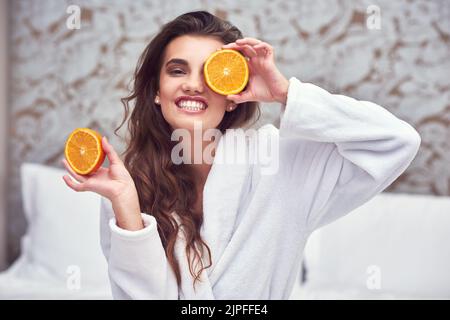 Ich sehe etwas Vitamin C. eine attraktive junge Frau, die orangefarbene Hälften hochhält. Stockfoto