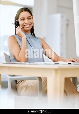 Callcenter-Mitarbeiter geben Ratschläge und helfen Kunden bei der Verwendung von Headsets und Netzwerken auf einem Desktop-Computer im Büro. Porträt eines Lächelns Stockfoto