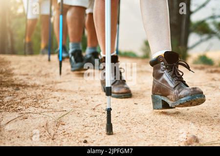 . Wandergruppe Wandern mit Wanderstöcken auf einem Wanderweg in der Natur für Fitness. Fit, aktiv und sportlich Menschen auf einem Abenteuer. Erwachsene Freunde Stockfoto