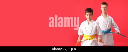 Kleine Jungen in Karategi auf rotem Hintergrund mit Platz für Text Stockfoto