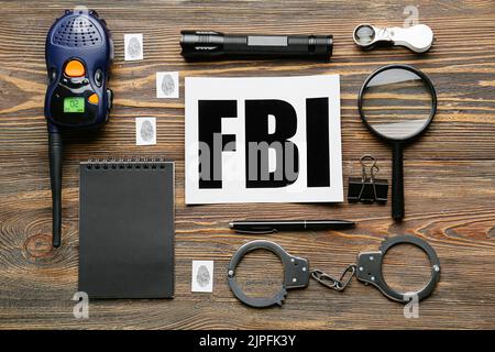 Papierbogen mit Abkürzung FBI, Notizbuch und Zubehör von Agent auf Holzhintergrund Stockfoto