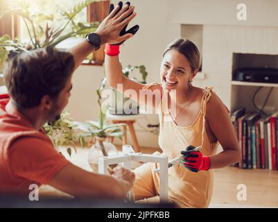 Paar tun hohe fünf, gut gemacht oder gute Arbeit Geste beim Malen oder Umbauen von Möbeln, Holztisch für Wohnverbesserung oder Inneneinrichtung. A Stockfoto