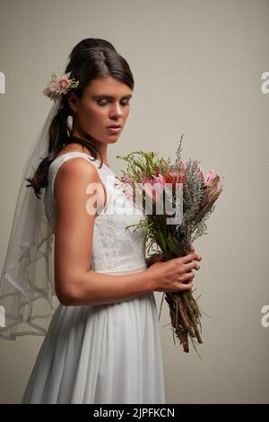 Bereit für den großen Tag. Studioaufnahme einer jungen, schönen Braut, die vor grauem Hintergrund posiert. Stockfoto