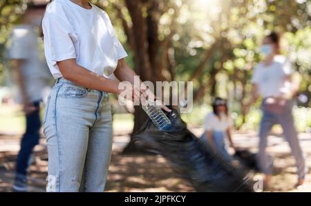 Freiwillige helfen beim Sammeln von Müll auf Community Cleanup Projekt im Freien, sammeln Plastik und Abfall zu recyceln. Frau, die die Umgebung putzt, pflückt Stockfoto