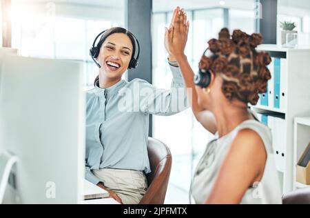 Fünf hoch aufgeregte Callcenter-Agenten mit Computern, die mit einem erfolgreichen Deal, einer erfolgreichen Promotion und einem erfolgreichen Verkauf zufrieden sind. Lächelnd, jubelnd und motiviert Stockfoto