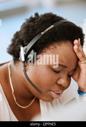 Burnout, Kopfschmerzen und gestresste weibliche Callcenter-Agentin, die mit Problemen, schlechter geistiger Gesundheit oder stressigem Job arbeitet. Vertriebsmitarbeiter oder Berater Stockfoto