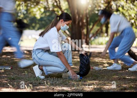 Ehrenamtlich, recyceln und reduzieren Abfall durch Aufnehmen von Müll, Schmutz und Müll im Freien in einem Park während covid. Ein junges Team von NGO-Aktivistinnen Stockfoto