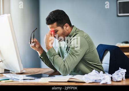 Ich muss meine Augen ein wenig ruhen. Ein unangenehmer junger Geschäftsmann, der seine Stirn mit schmerzenden Händen hält, während er an seinem Schreibtisch sitzt Stockfoto