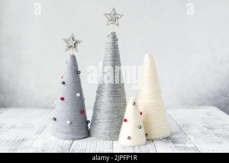 Handgefertigte Weihnachtsbäume. Garnumhüllte WEIHNACHTSKEGELBÄUME mit minimalistischem Dekor. DIY-Konzept Stockfoto