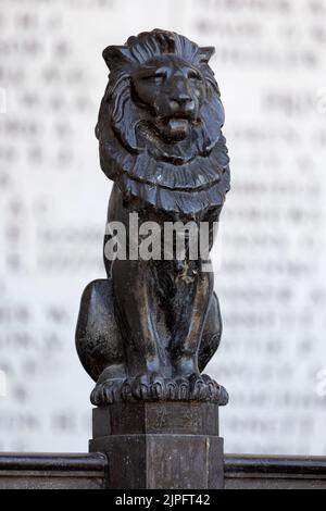 YPERN, BELGIEN - 10. AUGUST 2022: Kleine gegossene Löwen auf Geländer rund um das Menin-Tor mit den unschärfenden Namen des Denkmals im Hintergrund Stockfoto