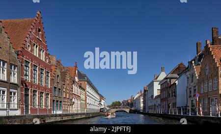 BRÜGGE, BELGIEN - 11. AUGUST 2022: Panoramablick auf den Kanal mit Sightseeing-Boot Stockfoto