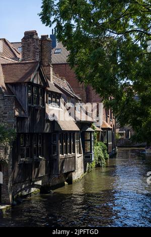 BRÜGGE, BELGIEN - 11. AUGUST 2022: Blick auf die mittelalterlichen Häuser am Canalside in der Nähe der Bonifaciusbrücke Stockfoto