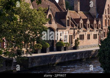 BRÜGGE, BELGIEN - 11. AUGUST 2022: Panorama mittelalterlicher Gebäude entlang eines Kanals bei Abendsonne Stockfoto