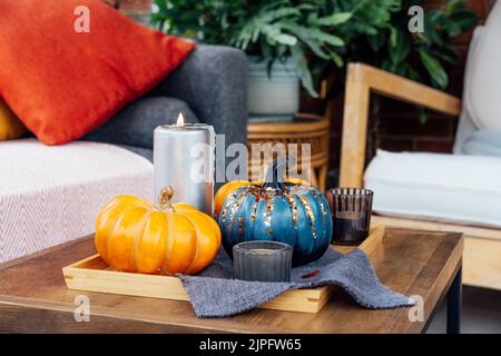 Herbst, Herbst gemütliche Stimmung Komposition für Hygge Wohnkultur. Kleine Kürbisse, brennende Kerzen auf Tablett mit grauer Serviette auf dem Kaffeetablett in der Wohnr Stockfoto