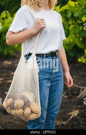 Porträt eines unbekannten Mädchens, das einen Einkaufstasche aus Baumwollstring mit Gemüse hält. Umweltfreundlicher Style. Kein Kunststoff. Modernes, wiederverwendbares Shopping, Zero Waste Konzept. Stockfoto