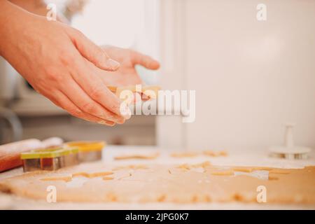 Frau Hände Formen Formen Kutter Ingwerteig und macht leckere weihnachten Ingwerkekse. Kochen und Dekorieren weihnachtsdessert. Stockfoto