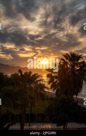Sonnenaufgang über Meerwasser und Palmen in Torrox Costa, Costa del Sol, kleiner touristischer Ort zwischen Malaga und Nerja, Andalusien, Spanien Stockfoto