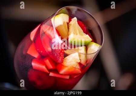 Glas rote Sangria und Früchte auf dunklem Steintisch Stockfoto