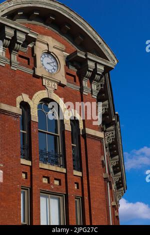 Eine vertikale Aufnahme eines Ziegelgebäudes mit einer Uhr Stockfoto