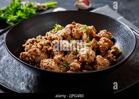 Gebratene italienische Wurst aus frisch gemahlenem Schweinefleisch und Gewürzen in schwarzer Schüssel auf Betontisch, horizontale Ansicht von oben Stockfoto