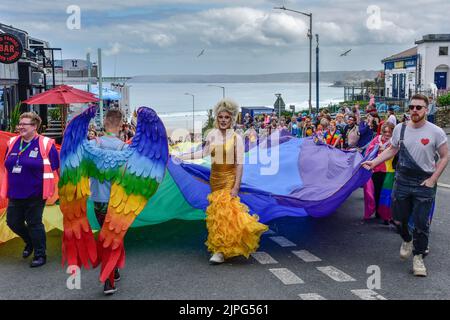 Das riesige farbenfrohe Banner, das von den Teilnehmern der Cornwall Prides Pride Parade im Zentrum von Newquay in Großbritannien getragen wurde. Stockfoto