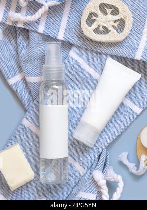 Kosmetikpumpenspender Flasche und weiße Creme-Tube auf blauem Badetuch Draufsicht, Kopierraum. Verpackungsmodup. Natürliche hausgemachte Produkte Stockfoto