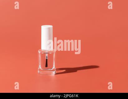 Nachfüllbare Flasche aus klarem Glas mit Bürstendeckel auf rosa, hartem Schatten, Nahaufnahme, Nachbildung. Hautpflege oder Nagelprodukt. Naturkosmetik, minimale Zusammensetzung Stockfoto