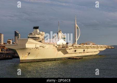 Portsmouth's Spinnaker Tower über dem zweiten Flugzeugträger der Queen Elizabeth-Klasse der Royal Navy, HMS Prince of Wales, an ihrem Heimatstandort in Portsmouth, Hampshire, Großbritannien. Sie wurde zwischen 2011 und 2017 erbaut und wurde 2021 in Dienst gestellt Stockfoto