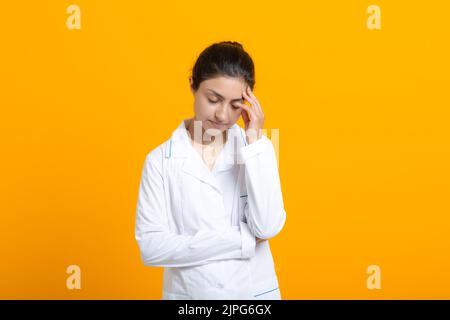 Porträt der indischen Ärztin in weißem medizinischen Kleid isoliert auf gelbem Hintergrund. Stockfoto